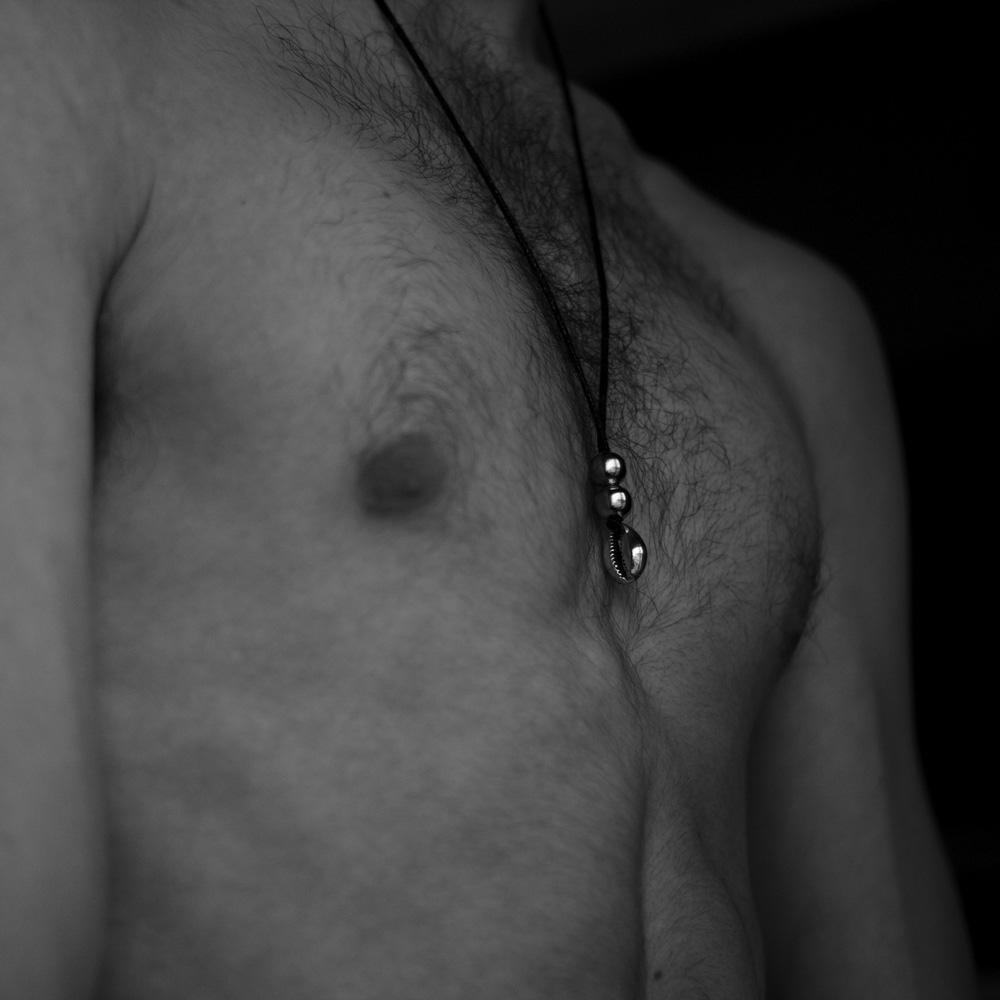 image of a mans chest wearing a charm necklace