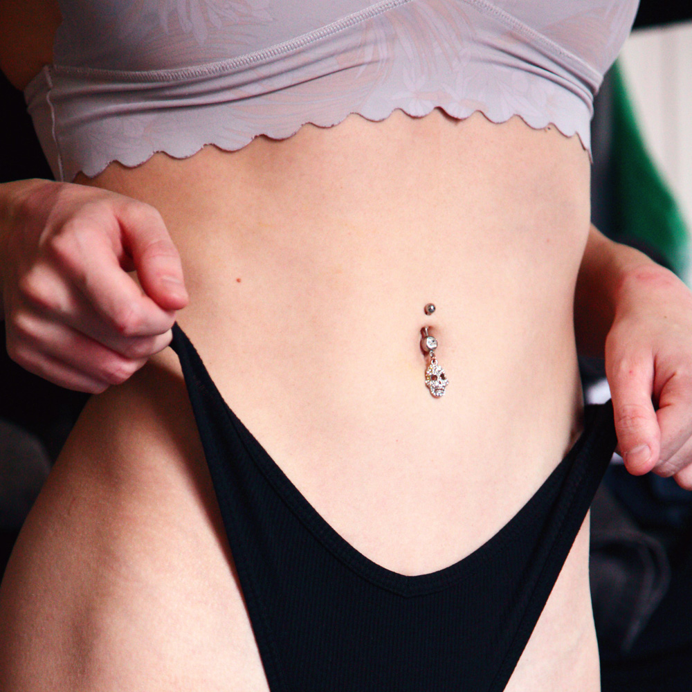 close up of a woman's flat stomach with belly button priercing